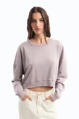 Buzo corto color lila, de rústico de algodón peruano, con escote a la base y manga larga con puños. Presenta ruedo con terminación curva en frente y estampa a contratono posicional en espalda.