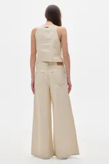 Pantalón jean color crema, de tiro alto y corte wide leg.