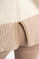 Sweater de lana color crema con efecto tweed, de calce oversize y cuello redondo. Presenta bloques de color en la parte inferior, puños y laterales de las mangas en tono beige con textura acanalada y detalles brillantes.