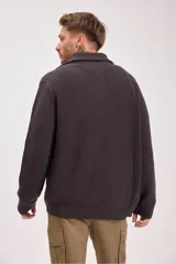 Sweater verde oscuro de punto con cuello alto y cierre de cremallera parcial. Tejido de canalé vertical.