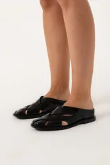 Zueco negro de cuero con capellada enrejillada y horma cuadrada.