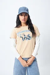 Remera color beige de manga corta con cuello redondo y estampado con ilustración gráfica al frente y frase retro.