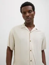 Camisa de hombre color beige claro, de viscosa, con cuello resort, mangas cortas, cierre con botones y corte relajado.