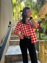 Blusa de mangas cortas con estampado de cuadros rojos y blancos, cuello redondo y cierre frontal con botones de madera.