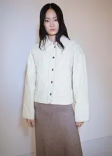 Chaqueta acolchada color crema de pana con cuello camisero, cierre frontal con botones, diseño oversize y corte bomber.