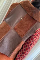 Chaleco marrón y beige con cierre frontal y cuello de piel sintética.