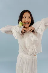 Camisa celeste de algodón con cuello alto y volados frontales. Mangas largas con puños fruncidos.