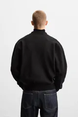 Camisa de punto color negro, corte relaxed fit, con cuello solapa, manga larga y cierre frontal con botones.