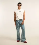 Pantalón de jean celeste con lavado dirty, corte flare, cintura fija con trabillas, cierre con botón y cremallera, y bolsillos.
