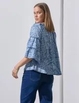 Blusa celeste con estampado floral blanco, escote con frunces y mangas 3/4 con volados.
