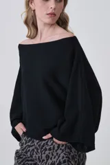 Sweater holgado de tejido ligero, color beige claro, con escote asimétrico que deja un hombro al descubierto.