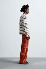 Camiseta relaxed fit de manga larga confeccionada en tejido compacto de algodón a rayas horizontales blancas y negras. Tiene cuello redondo y detalle de estampado de flores rojas en el bajo. Edición especial Zara x Otis Kwame Kye Quaicoe.