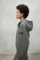 Campera gris con capucha ajustable con cordones, cierre frontal y bolsillos laterales.