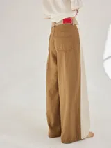 Pantalón ancho de denim con diseño patchwork en diferentes tonos de azul, con tiro alto, corte holgado y cierre frontal con botones.