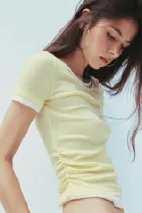 Camiseta blanca de corte slim fit, cuello redondo y manga corta con acabados en puntilla. Tiene detalle de frunces en los laterales y tejido combinado a contraste efecto doble en cuello, mangas y ruedo.