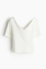 Top blanco de punto ajustado, con escote en V pronunciado y mangas cortas.