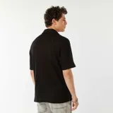 Camisa negra de manga corta con tejido de punto calado, cuello clásico y cierre frontal con botones.