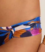 Bikini con corpiño con aro y bombacha con laterales drapeados, con estampado floral en tonos azules, violetas, naranjas y blancos.