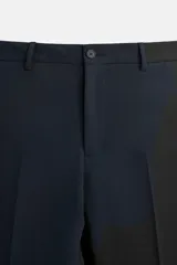Pantalón de vestir azul marino, de corte slim fit, con bolsillos laterales y traseros de vivo con botón. Se ajusta a la cintura con cierre frontal con cremallera y botón.