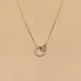 Conjunto de dos collares en plata 925. El collar superior presenta un dije rectangular con engarce de circones. El collar inferior presenta un dije circular liso. Además, la modelo lleva aros pequeños de plata 925.