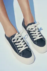 Zapatillas bajas de denim azul oscuro con cordones blancos y suela de plataforma color crema.