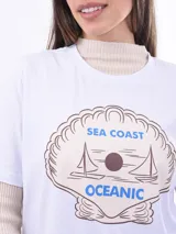Remera negra de algodón con cuello redondo y mangas cortas. Estampado frontal con la frase "World Tour Vacation State of Mind" en letras de colores y un pequeño dibujo de una palmera.