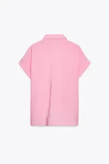 Camisa fluída color rosado confeccionada en hilatura con modal. Tiene cuello solapa, manga corta con vuelta y detalle de nudo en el delantero. Cierre frontal con botones.