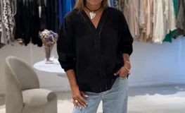 Camisa negra de manga larga con puños elásticos, cierre frontal con botones y detalles de bordados perforados a tono en la parte delantera y trasera.