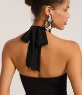 Body negro de microfibra con escote halter, lazo en el cuello, recortes circulares con adornos metálicos y cierre con broches en la entrepierna.
