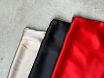 Vestido midi negro de satén con breteles finos, escote en V con volados y lazo ajustable.