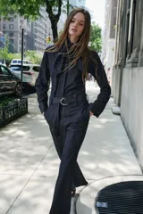Camisa de denim azul oscuro con cuello con lazos, mangas largas con puños abotonados, bajo redondeado y cierre frontal con botones ocultos.