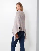 Poncho de tejido suave, color crudo con hilos multicolores que generan un efecto jaspeado en tonos pastel (rosa, celeste, lila). Presenta un diseño asimétrico con cuello redondo y terminación en flecos largos en el ruedo.