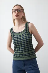 Top sin mangas tejido con diseño geométrico en relieve, en colores verde y azul marino. Presenta escote amplio y breteles tejidos con terminaciones trabajadas.