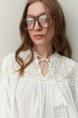 Blusa blanca de algodón con encaje floral en la parte superior, mangas largas abullonadas y escote con lazo.