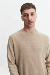 Buzo de punto color beige, con escote redondo y puños.