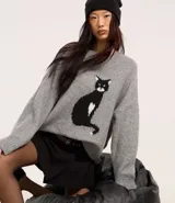 Sweater gris de tejido de punto con cuello redondo y diseño de gato negro en el frente.