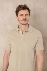 Remera tipo polo color beige, de manga corta y corte clásico. Tiene cuello con botones y está confeccionada en algodón.