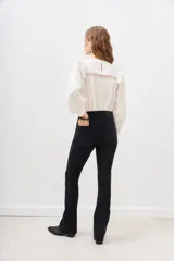 Pantalón de jean negro de corte flare con detalle de tachas metálicas en los bolsillos delanteros.