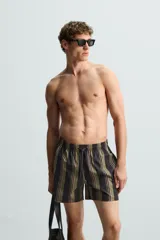 Bañador corto de tejido técnico con rayas verticales en tonos negro, verde oliva y rosa. Cuenta con cintura elástica ajustable con cordón, bolsillos laterales y trasero.