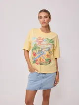 Remera amarilla de algodón con estampado de playa hawaiana con palmeras, flores y tabla de surf.