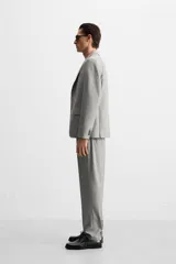 Blazer regular fit color gris claro confeccionado en tejido con lana. Tiene cuello con solapas de muesca, manga larga con puño abotonado, bolsillo de vivo en el pecho, bolsillos de solapa en la cadera, bolsillo interior, aberturas en la espalda y cierre frontal con botones.