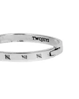 Pulsera rígida plateada con cierre de bisagra y grabados de líneas verticales.