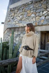 Sweater tipo poncho color beige de tejido grueso con cuello alto y mangas largas.