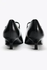 Zapato de cuero negro con tacón kitten, tira con hebilla ajustable y punta fina.
