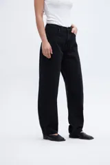 Jean negro de tiro alto, con cintura ajustada y piernas holgadas desde la cadera hasta la rodilla, estrechándose hacia el bajo. Silueta tipo globo, calce balloon.