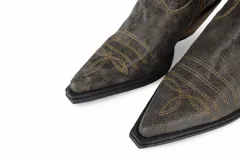 Bota corta estilo texana color marrón, confeccionada en cuero, con bordados decorativos y cierre lateral. Interior forrado en cuero, plantilla anatómica y suela de goma con taco foliado de 3,5 cm.