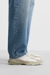 Zapatilla deportiva tipo running de color negro, perteneciente a la colección especial Origins. Presenta una parte superior confeccionada en una combinación de cuero con acabado de gamuza y tejido transpirable. Cuenta con una suela de volumen con diseño irregular y cierre mediante cordones.