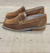 Mocasín de gamuza color marrón claro con detalle de hebilla y suela clara.