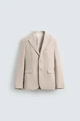 Blazer color arena confeccionado en lino, de corte recto, con solapas de muesca, cierre de dos botones, bolsillo de vivo en el pecho, bolsillos de solapa en la cadera, aberturas en la espalda y forro interior.