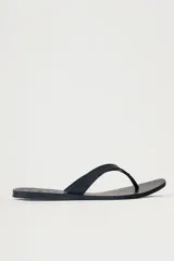 Sandalia plana tipo flip flop de cuero negro, con diseño minimalista y tira central de cuero. Presenta detalles de tachas metálicas en la base.